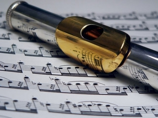 silver and gold flute on sheet music
