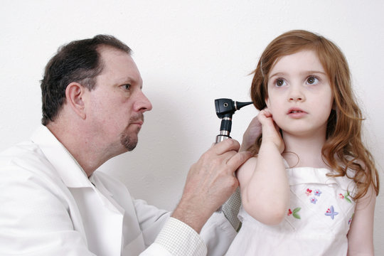 doctor checking little girl's ear with a stethosco