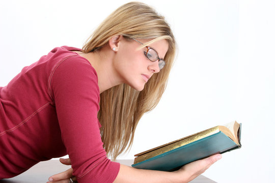 beautiful young woman in glasses reading book