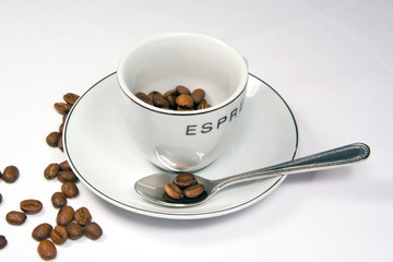 tight closeup of espresso cup and saucer with beans