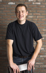 casual young adult man standing next to the brick