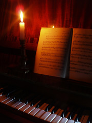 piano and sheet music in the  light of candle
