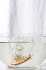juicy slice of orange splashing into water