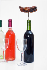 bottles of red, white and rose wine with glasses and a corkscrew