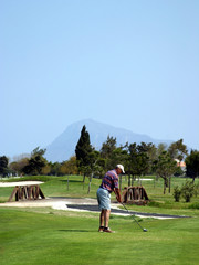 Obraz premium man teeing off on pretty golf course in sunny spain