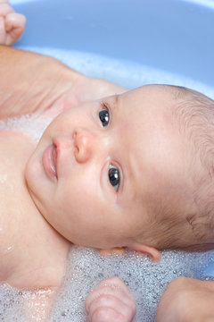 baby girl having her first bath at home and smiling