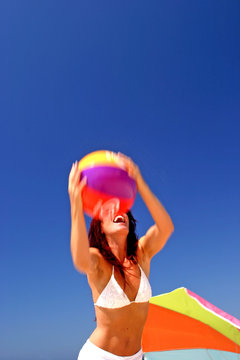 Fit And Healthy Woman Catching Beach Ball On Sunny Beach In Spai