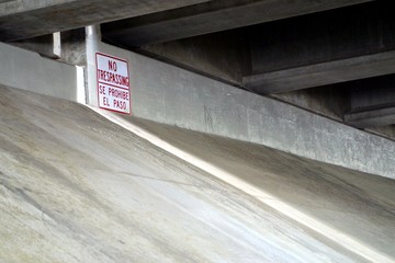 "no trespassing" sign under bridge