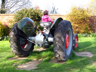 small girl on old tractor in green field