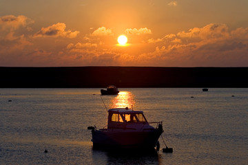 fishing boats moored at sea during sunset