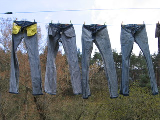 Quatre pantalons en jean sèchent sur un étendage