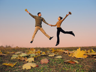 jump couple. autumn leaves. sunset sky