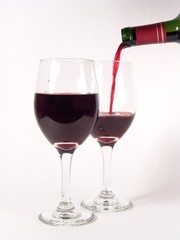 Red wine pouring in glasses (isolated in white background)