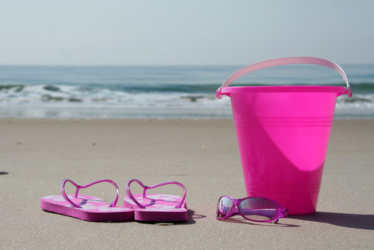 flip-flops, sunglasses and pail on the beach