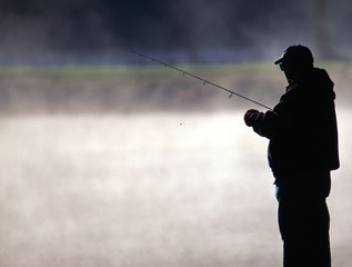 trout fisherman by a misty lake