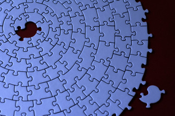 blue jigsaw with one missing piece laying aside