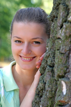 young woman hiding by the tree