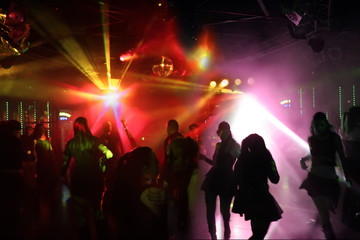 tanzende junge menschen im rot/violettem licht