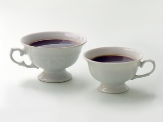 two white cups with black strong coffees