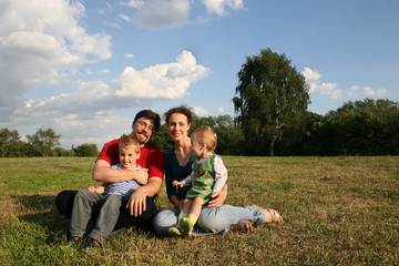 Naklejka na ściany i meble family with two children sit on meadow and trees
