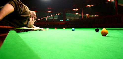 young man shooting a red ball. snooker game. - obrazy, fototapety, plakaty