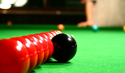 ten snooker bools in line. black bool is out of row. distinctive