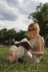 woman sitting in a park and reading a book