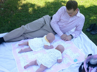 father playing with twins girls at park
