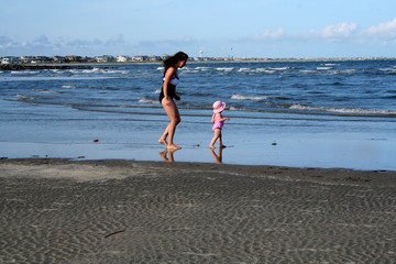 mother walking on beach with daughter