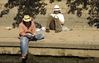 two men reading on the banks of a river