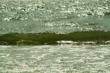 sunlit waves breaking on the shore at the beach