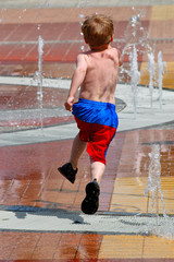 boy running and jumping through a fountain