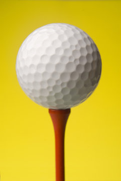 golf ball on red tee, yellow background