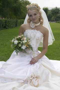 the fine bride sits on a meadow.