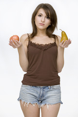 girl posing holding pear and an apple