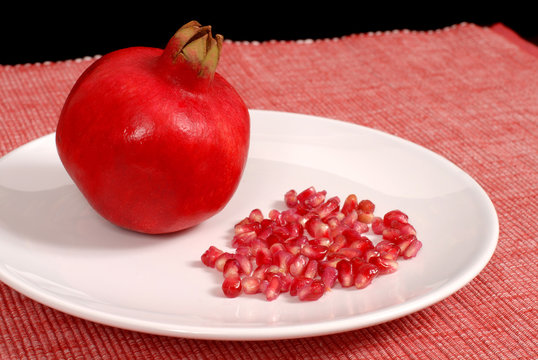 pomegranate and seeds on white plate
