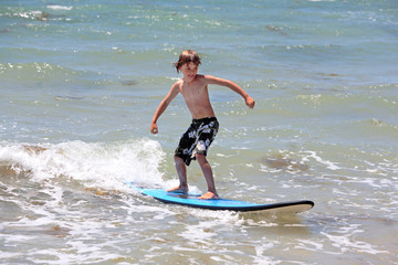 healthy young boy learning to surf