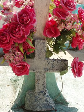 weathered cemetery cross with roses