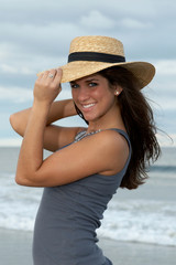 young brunette woman in straw hat at the beach