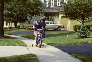Fototapeta premium mother helps son learn to ride a bike