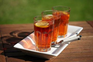 three glasses of tea on white plate in garden