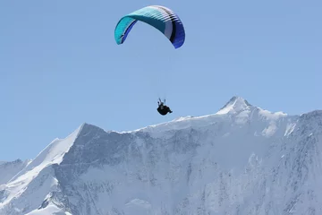 Tuinposter paraglider above snow capped peaks © Karen Riley