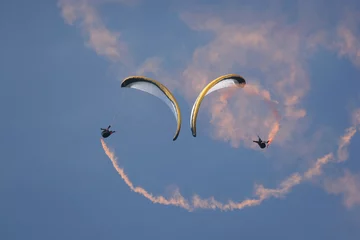 Fototapeten paragliders performing syncro sat with smoke trail © Karen Riley