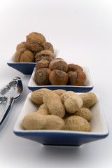 walnuts, hazelnuts and peanuts in three bowls