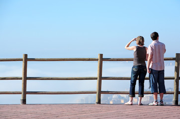 young couple looking out to sea from high viewpoint