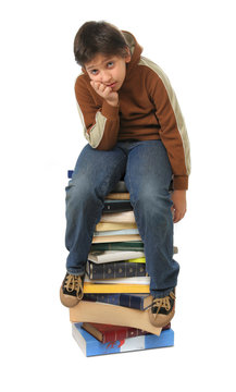 student sitting on a pile of books
