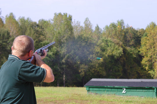 shooter at  the line breaking clays with a shotgun at an outdoor range