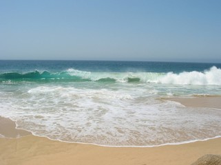 Fototapeta na wymiar White Waves from Turquoise Ocean Water Crashing on the Sandy Beach