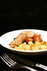roast salmon and potoatoes against black.
