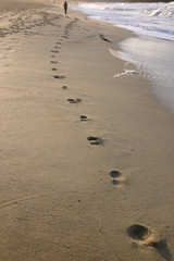 footprints and a woman in the distance jogging alo